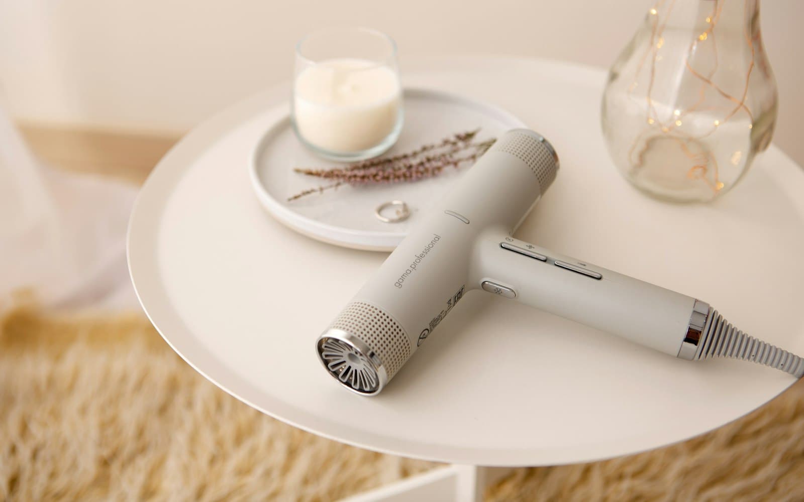 A matte hair dryer, a round brush and a curling wand on a bathroom shelf